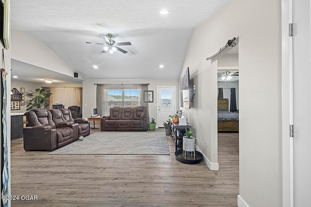 living room featuring lofted ceiling, a textured ceiling, light wood-type flooring, and ceiling fan