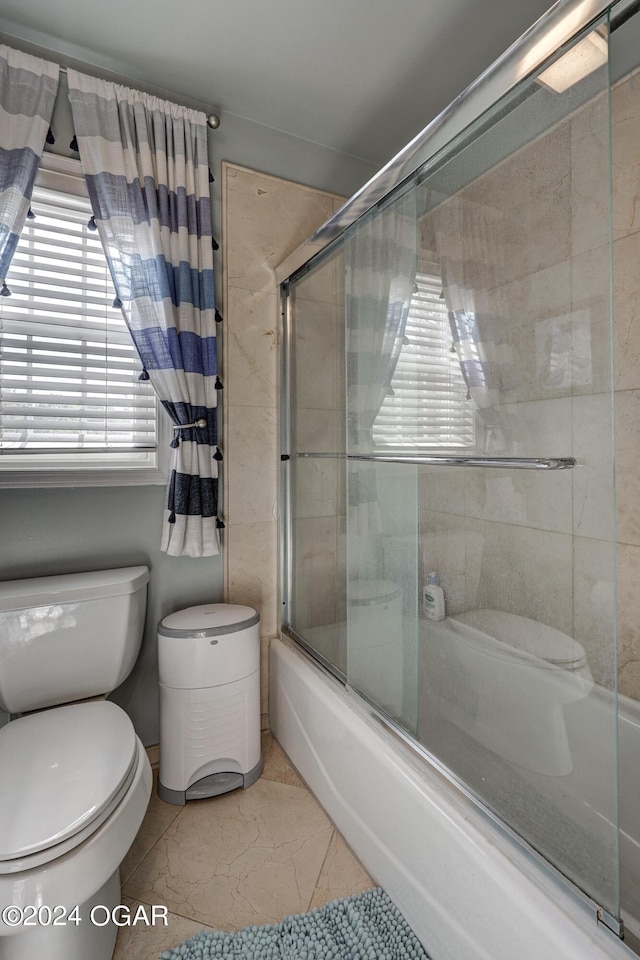 bathroom featuring toilet, tile patterned floors, and combined bath / shower with glass door