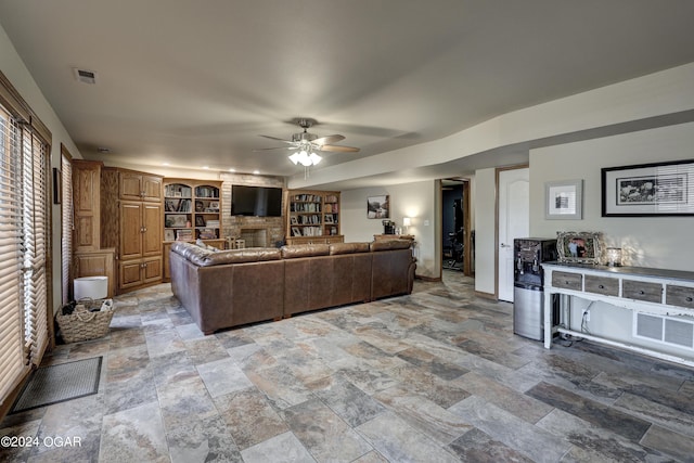 living room featuring a fireplace, built in features, and ceiling fan