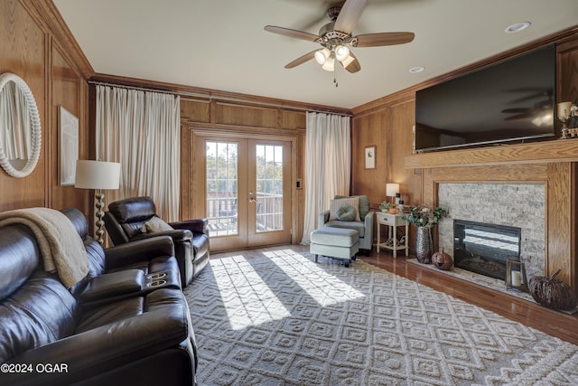 living room featuring french doors, wooden walls, ornamental molding, light hardwood / wood-style floors, and ceiling fan