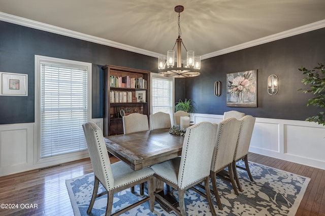 dining space with ornamental molding, a notable chandelier, and hardwood / wood-style flooring