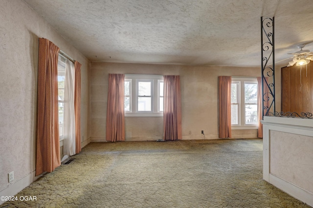 unfurnished room with a textured ceiling, carpet flooring, and a healthy amount of sunlight