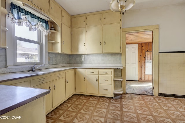 kitchen featuring washer / clothes dryer, decorative backsplash, cream cabinets, and sink