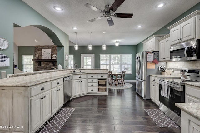 kitchen with light stone countertops, sink, a textured ceiling, stainless steel appliances, and pendant lighting