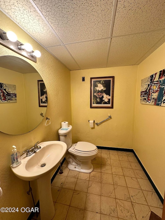 bathroom with toilet, tile patterned floors, sink, and a paneled ceiling