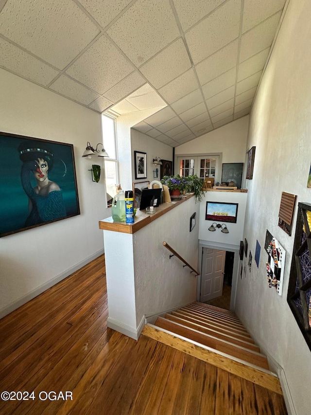 stairway featuring lofted ceiling, a drop ceiling, and hardwood / wood-style floors