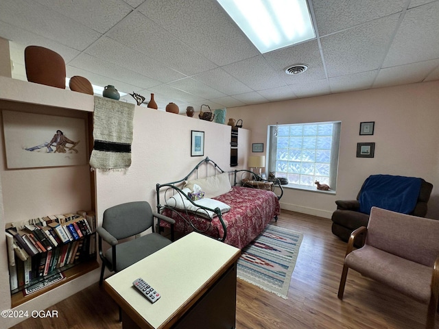 bedroom featuring wood-type flooring and a drop ceiling