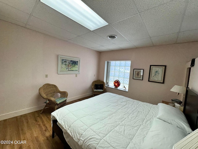 bedroom featuring a drop ceiling and wood-type flooring