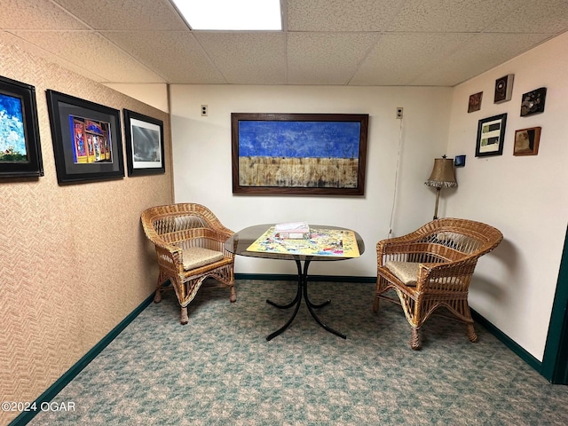 sitting room featuring a drop ceiling and carpet floors