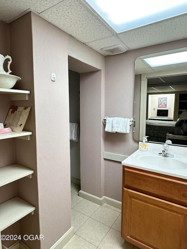 bathroom with vanity, a paneled ceiling, and tile patterned floors