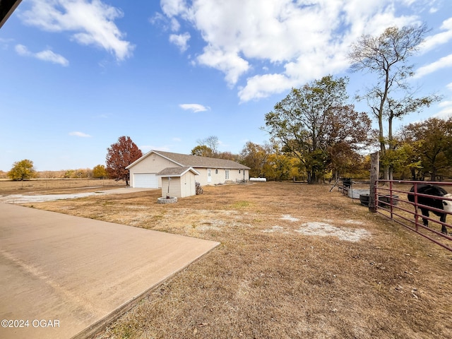 view of yard with a garage and a rural view