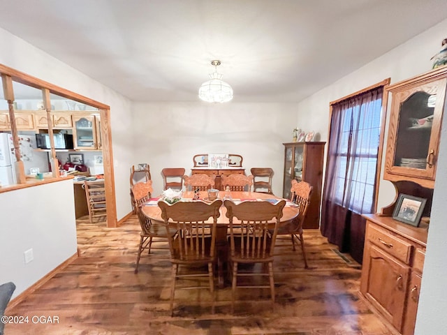 dining space with dark hardwood / wood-style flooring and an inviting chandelier