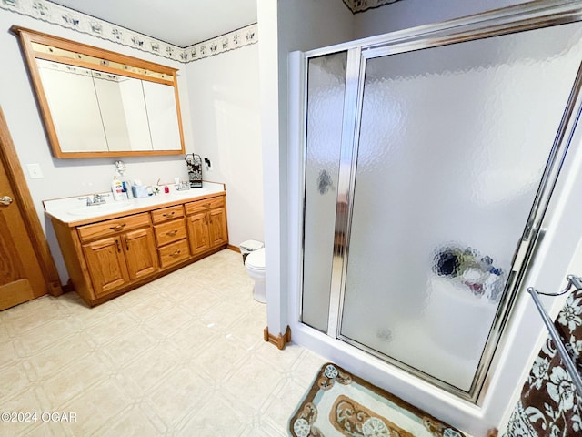 bathroom with a shower with door, vanity, and toilet