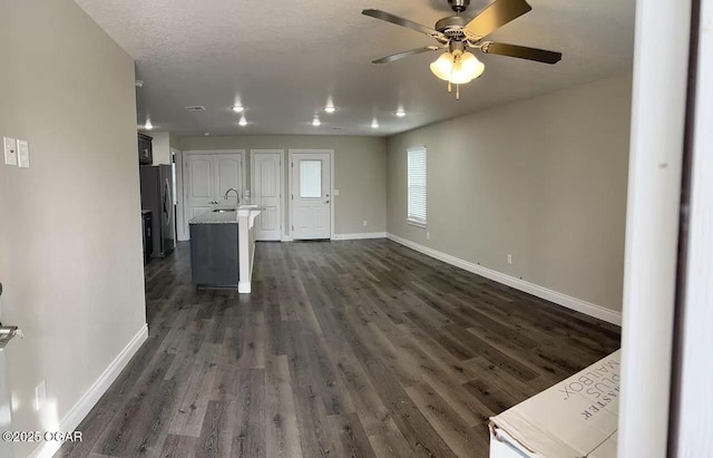 unfurnished living room with ceiling fan, dark hardwood / wood-style flooring, a textured ceiling, and sink