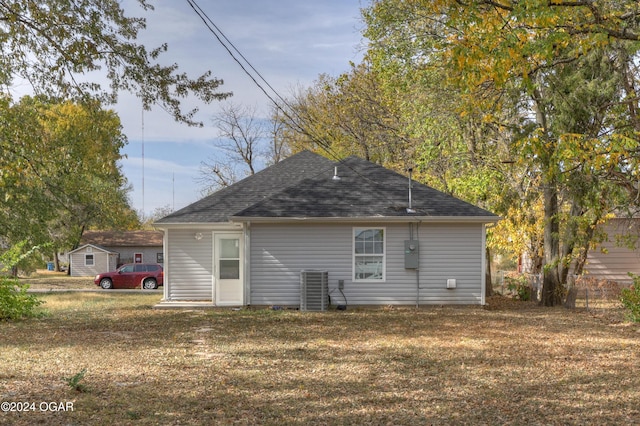 rear view of property featuring cooling unit and a yard