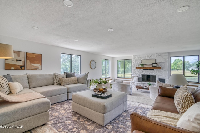 carpeted living room featuring plenty of natural light, a fireplace, and a textured ceiling