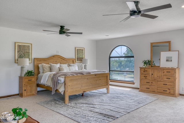 carpeted bedroom featuring ceiling fan and a textured ceiling