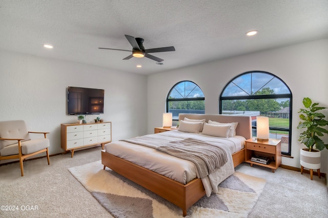 carpeted bedroom with ceiling fan and a textured ceiling