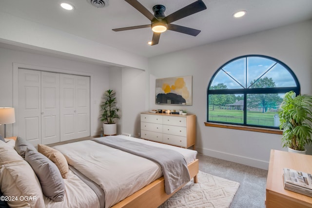 carpeted bedroom with ceiling fan and a closet