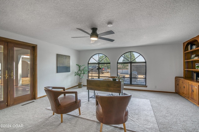 sitting room with light carpet, french doors, ceiling fan, and a textured ceiling