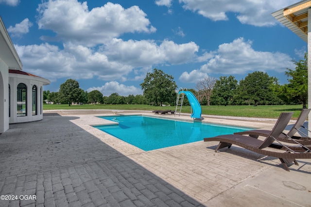 view of pool featuring a lawn, a patio area, and a water slide