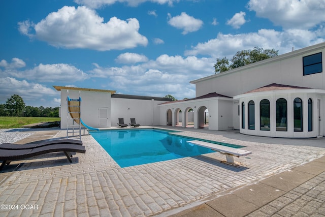 view of pool featuring a diving board, a patio, and a water slide