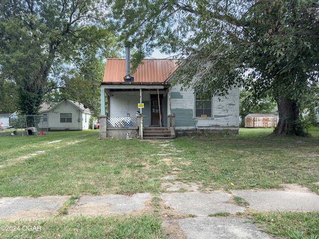819 W Arch St, Nevada, MO 64772 - view of front of property featuring a front lawn, metal roof, and covered porch
