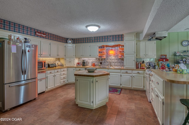 kitchen with sink, a kitchen island, a textured ceiling, stainless steel appliances, and white cabinets