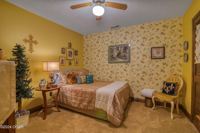 bedroom featuring light carpet, a textured ceiling, and ceiling fan