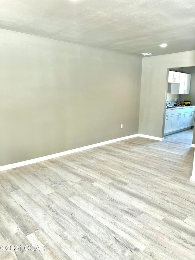 spare room featuring a textured ceiling and light wood-type flooring