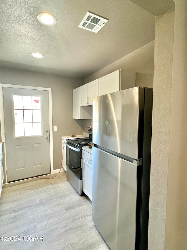 kitchen with white cabinetry, a textured ceiling, appliances with stainless steel finishes, and light hardwood / wood-style flooring