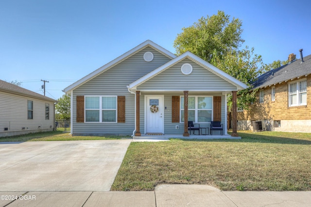 bungalow-style home featuring central AC unit, a porch, and a front yard