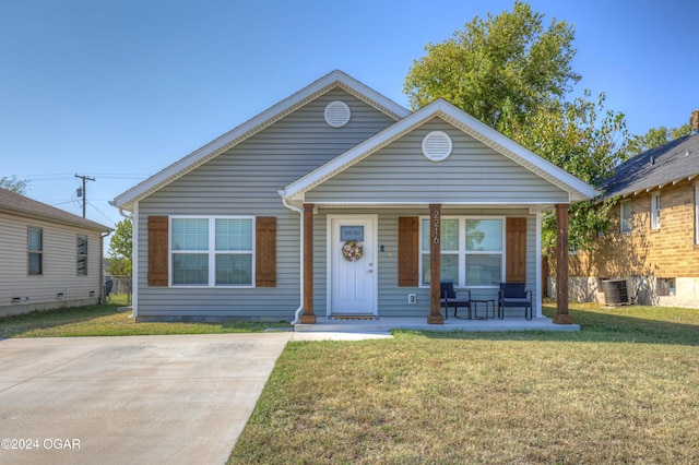 bungalow-style home with a front lawn, cooling unit, and a porch