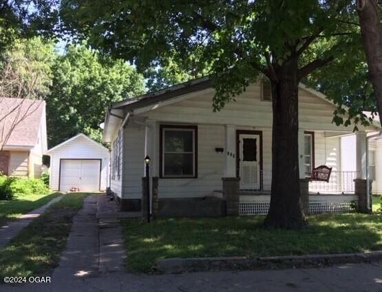 bungalow with covered porch, a front yard, an outbuilding, and a garage