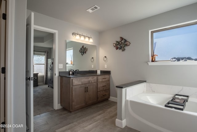 bathroom with vanity, hardwood / wood-style floors, and a bath