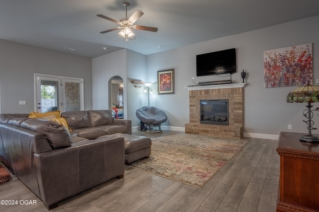 living room with ceiling fan, light hardwood / wood-style flooring, and a brick fireplace