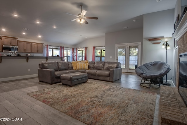 living room featuring lofted ceiling, ceiling fan, light wood-type flooring, and plenty of natural light