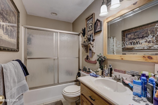 full bathroom featuring vanity, bath / shower combo with glass door, toilet, and tile patterned flooring