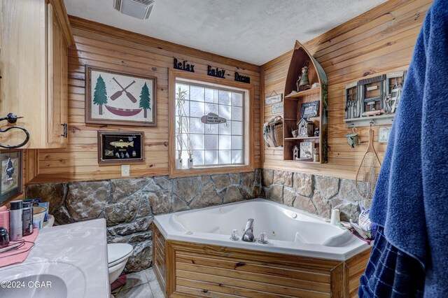 bathroom featuring toilet, wooden walls, a washtub, vanity, and a textured ceiling