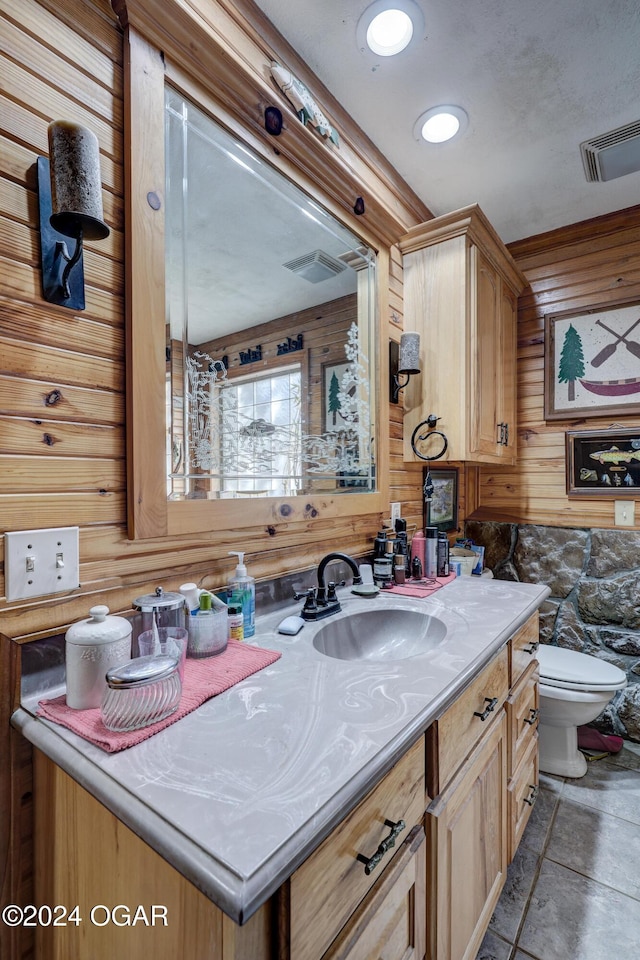 bathroom with vanity, toilet, and wooden walls