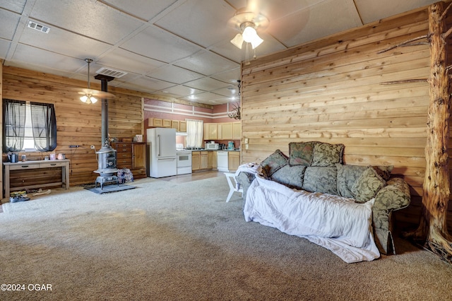 bedroom with a drop ceiling, a wood stove, ceiling fan, and white refrigerator