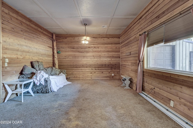 carpeted spare room with wooden walls and a baseboard heating unit