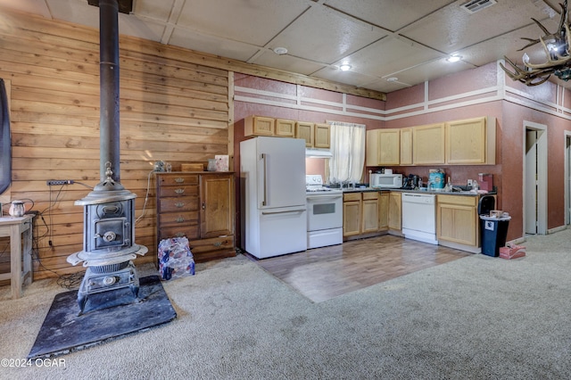 kitchen with light brown cabinets, a wood stove, hardwood / wood-style floors, and white appliances