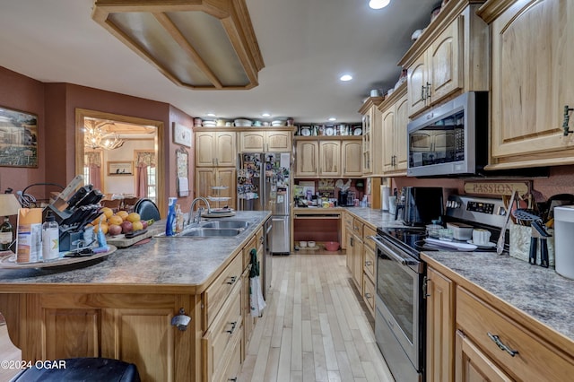 kitchen with sink, light wood-type flooring, stainless steel appliances, light brown cabinets, and a kitchen island with sink