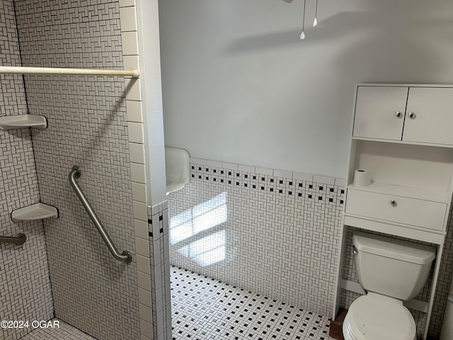 bathroom with tile walls, tiled shower, and toilet