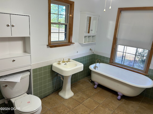 bathroom with toilet, a bathing tub, tile walls, and tile patterned flooring