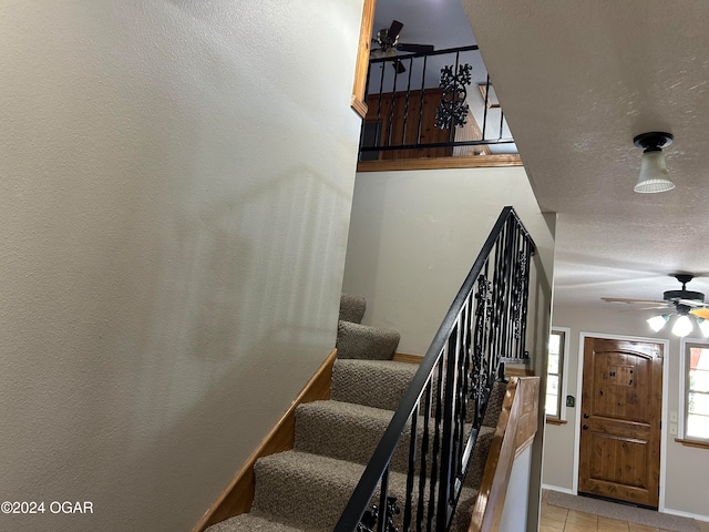 stairs with ceiling fan and tile patterned flooring