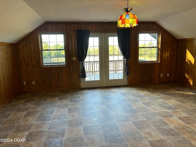 additional living space with wood walls, french doors, vaulted ceiling, and plenty of natural light