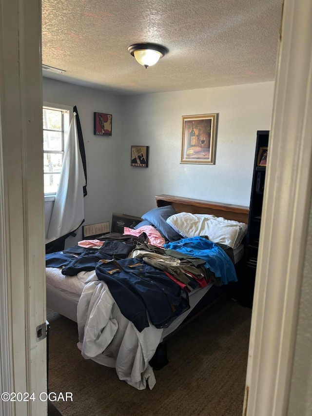 bedroom featuring a textured ceiling and dark carpet