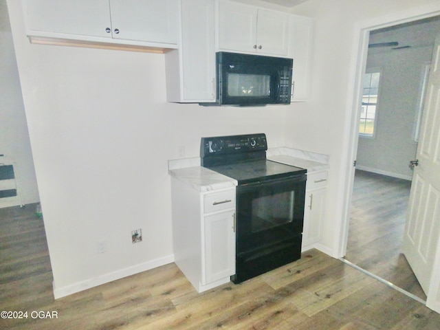 kitchen featuring light hardwood / wood-style floors, white cabinets, and black appliances